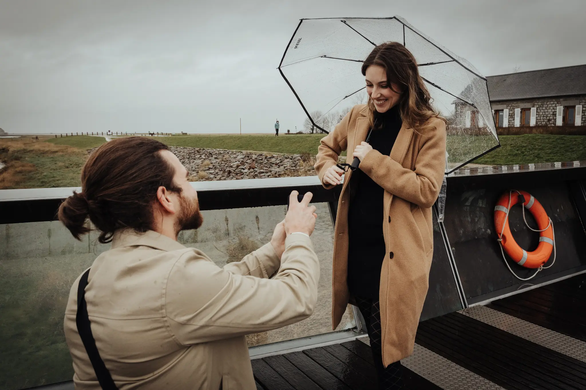 Demande en mariage sur la passerelle du Mont-Saint-Michel sous la pluie — homme à genoux, photographe Dol-de-Bretagne