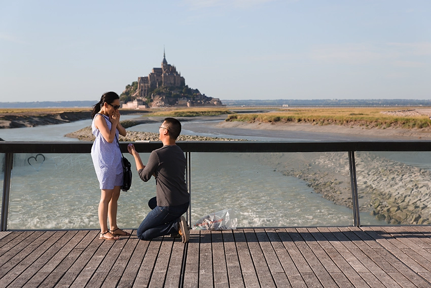 Demande en mariage au Mont-Saint-Michel — homme à genoux offrant la bague sur la passerelle, photographe Dol-de-Bretagne Normandie