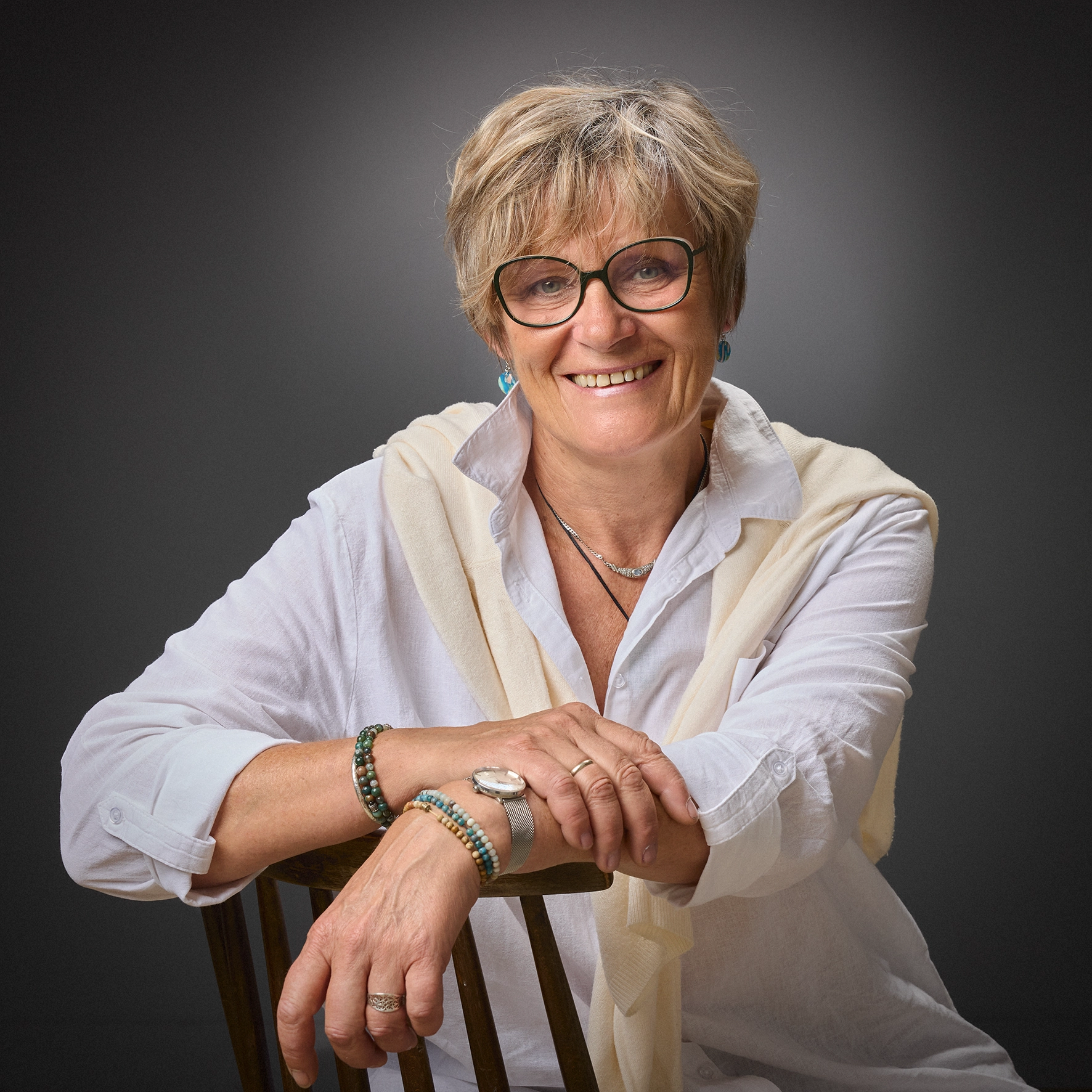 Portrait femme souriante chemise blanche lunettes, accoudée sur chaise en studio — Photographe portrait Dol-de-Bretagne, Saint-Malo, Ille-et-Vilaine