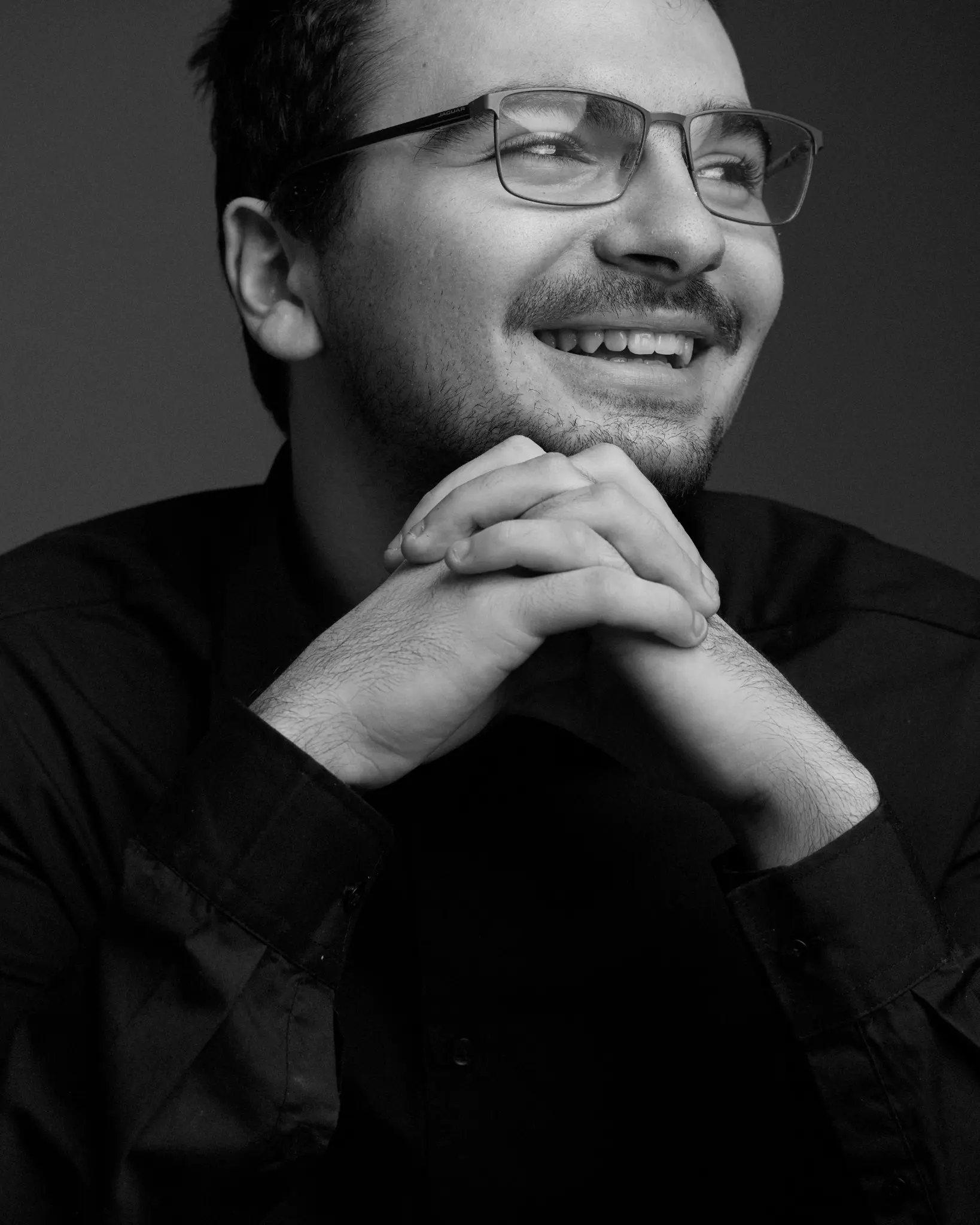 Portrait homme noir et blanc sourire lumineux mains jointes sous le menton — Photographe portrait homme Dol-de-Bretagne, Dinan, Ille-et-Vilaine